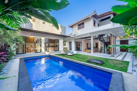 Villa moderne avec piscine bleue, jardin verdoyant et architecture élégante.