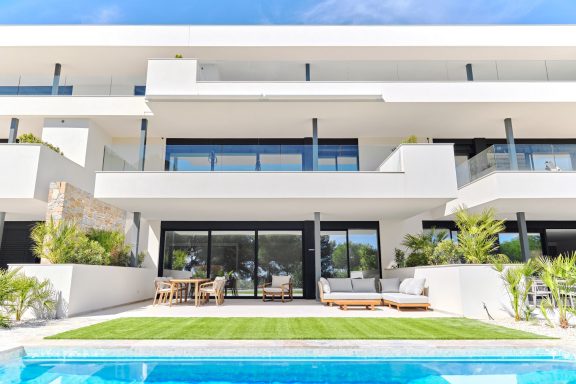 Maison moderne avec piscine, terrasse et jardin, entourée de plantes.