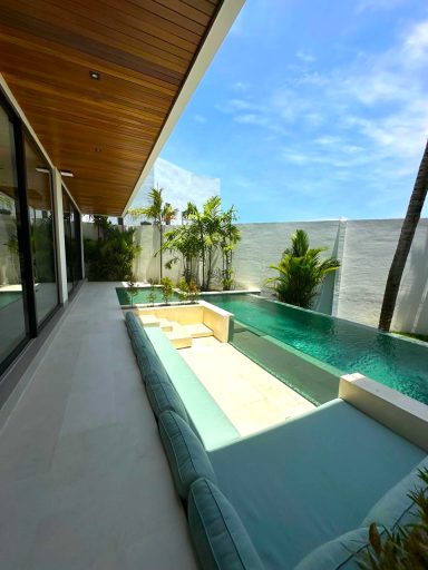 Vue d'une piscine moderne entourée de verdure et d'une terrasse bien aménagée.