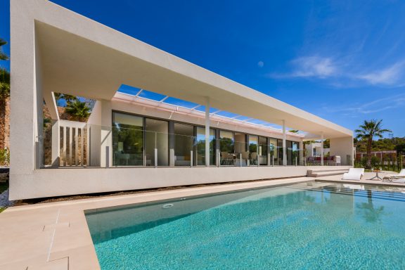 Maison moderne aux lignes épurées avec piscine, entourée de verdure.
