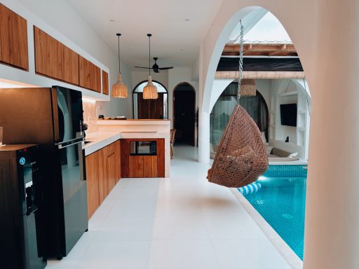 Intérieur moderne avec cuisine, hamac suspendu et piscine.