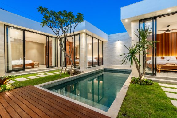 Maison moderne avec piscine, jardins et grandes fenêtres, ambiance élégante et lumineuse.