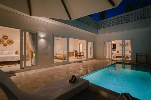 Villa moderne avec piscine éclairée, mobilier élégant et ambiance nocturne paisible.