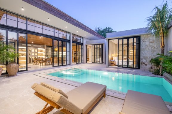 Villa moderne avec piscine, grandes baies vitrées et espace extérieur confortable.
