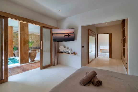 Chambre contemporaine avec accès à une terrasse et vue sur une piscine.