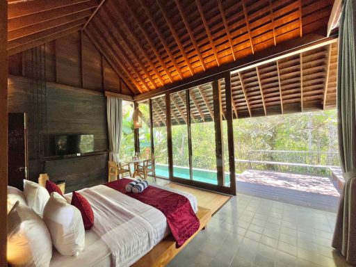 Chambre moderne avec lit, grandes fenêtres et accès à une piscine extérieure.