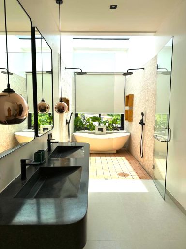 Salle de bain moderne avec double lavabo, baignoire, plantes et lumière naturelle.