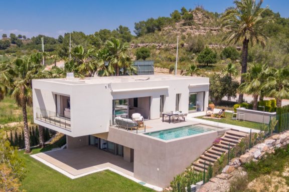 Maison moderne avec piscine, située dans un paysage verdoyant et ensoleillé.