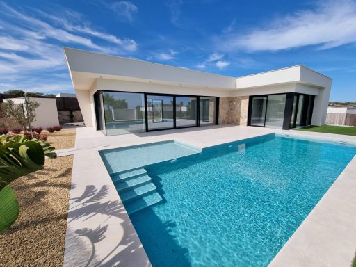 Maison moderne avec piscine, terrasse et jardin, sous un ciel bleu.